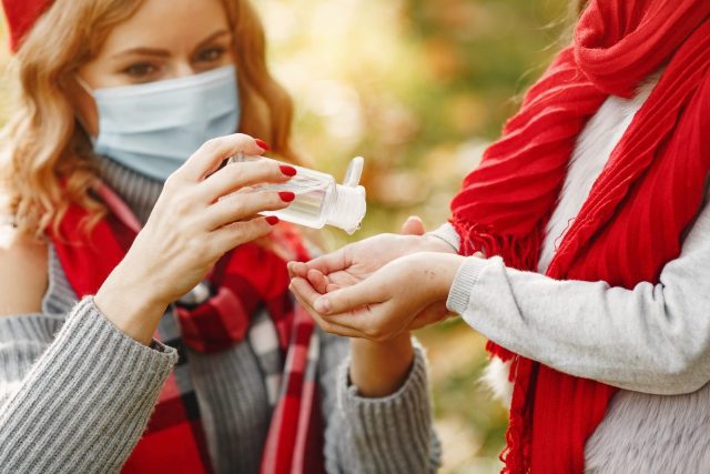 Woman Wearing Red Scarf And Gray Sweater Holding A Plastic Bottle