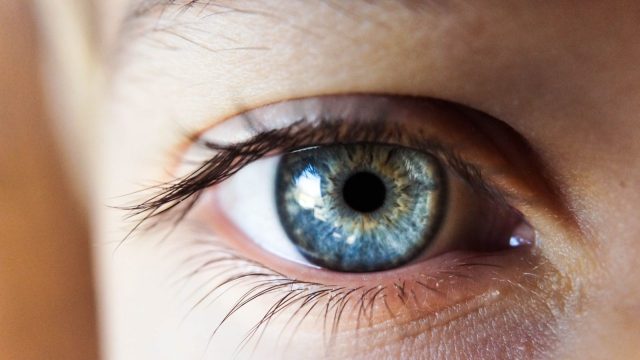 person opening his right eye with blue iris