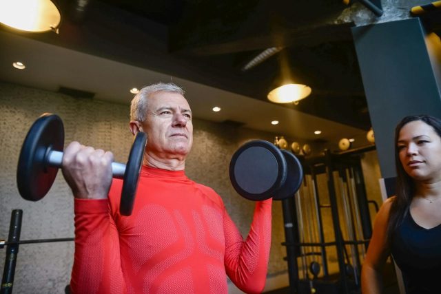 Elderly Man in Red Long Sleeve Shirt Lifting Dumbbells